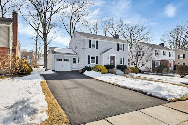 view of front of property with driveway, a chimney, and an attached garage