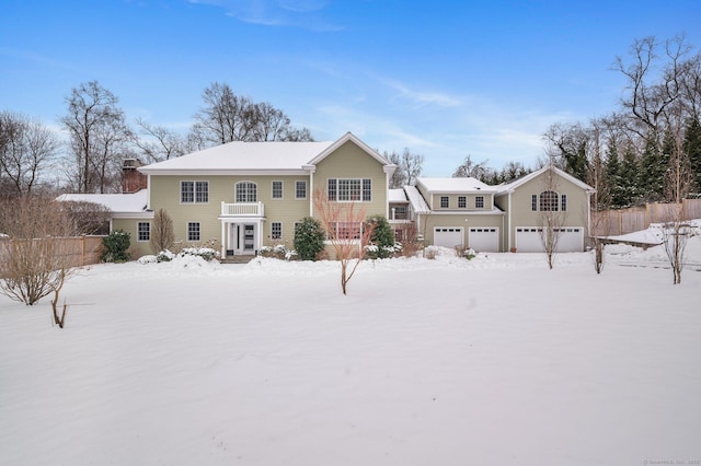 snow covered back of property with a garage