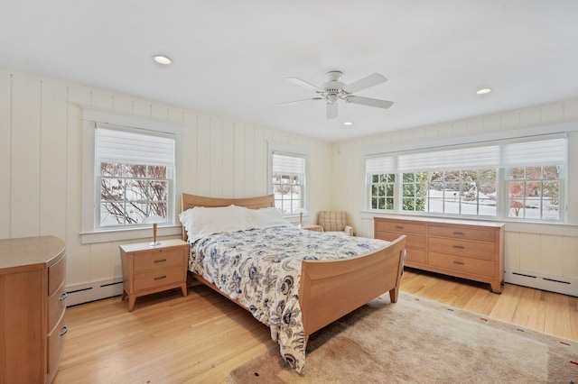 bedroom with a baseboard heating unit, ceiling fan, and light hardwood / wood-style flooring