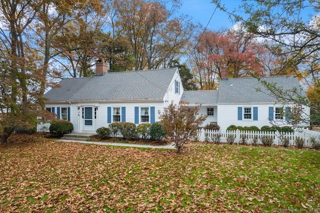 view of front of house featuring a shingled roof, a chimney, a front lawn, and a fenced front yard