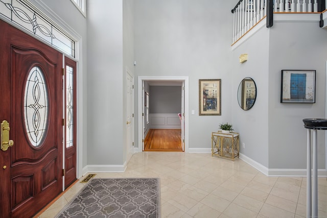 entrance foyer with marble finish floor, baseboards, and a high ceiling