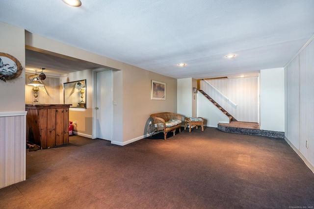 finished basement featuring dark carpet, baseboards, and stairs