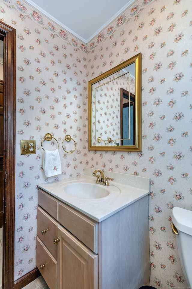 bathroom featuring toilet, wallpapered walls, and vanity