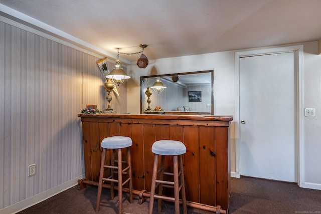 bar with a dry bar, dark carpet, and baseboards