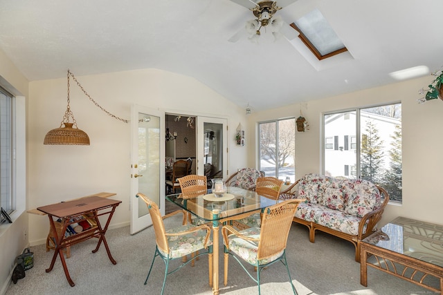 dining room with carpet floors, lofted ceiling with skylight, and a ceiling fan