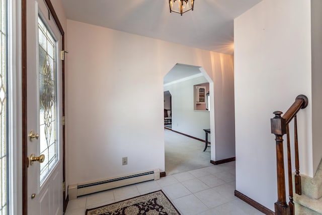 foyer featuring baseboards, arched walkways, light colored carpet, baseboard heating, and light tile patterned flooring