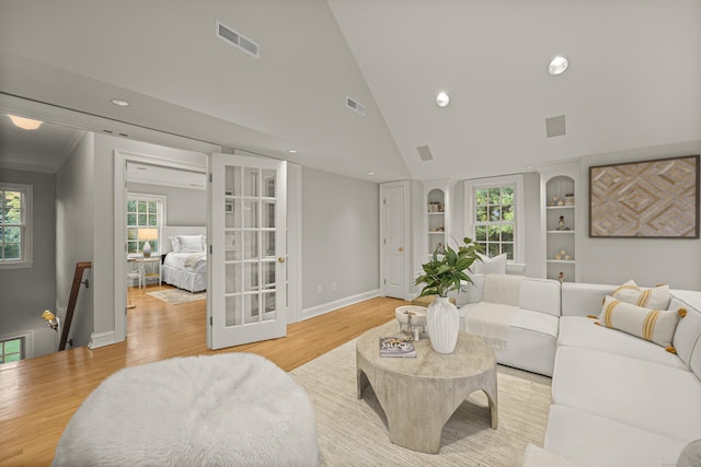 living room with high vaulted ceiling, light wood-type flooring, and built in shelves