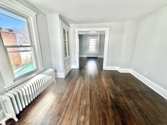 corridor featuring baseboards, dark wood-type flooring, and radiator