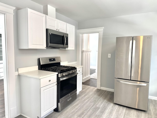 kitchen with stainless steel appliances, light countertops, and white cabinets