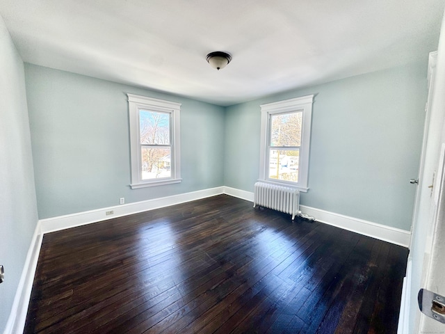 unfurnished room with baseboards, dark wood-style flooring, and radiator