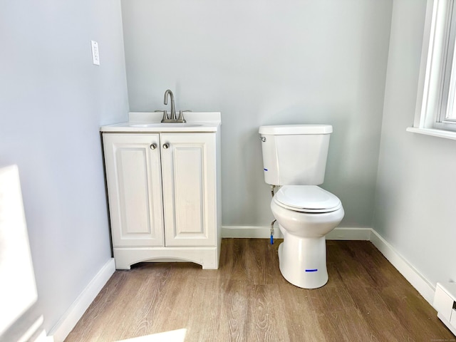 bathroom featuring toilet, wood finished floors, vanity, and baseboards
