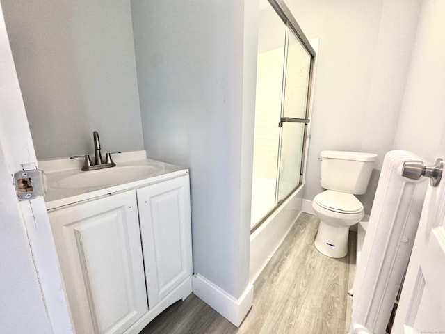 full bathroom with toilet, enclosed tub / shower combo, wood finished floors, and vanity