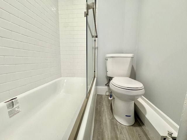 bathroom featuring shower / washtub combination, wood finished floors, toilet, and baseboards