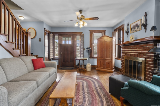 living room with ceiling fan, a fireplace, and light wood-type flooring