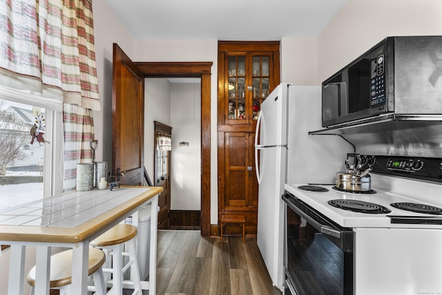 kitchen featuring electric stove, tile counters, and dark wood-type flooring