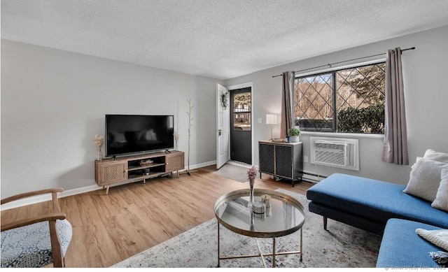 living room featuring baseboard heating, a textured ceiling, wood finished floors, a wall mounted air conditioner, and baseboards