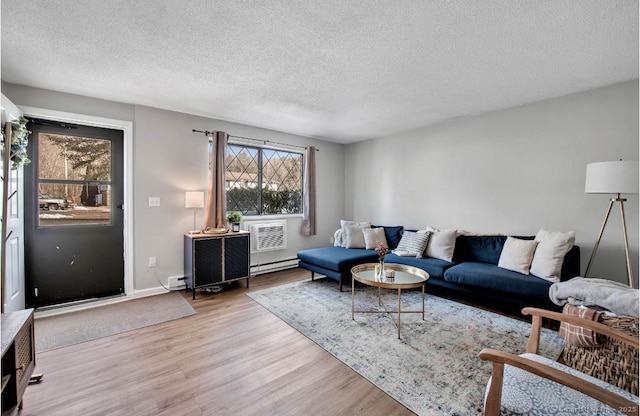 living room with light wood-type flooring, a healthy amount of sunlight, a textured ceiling, and a baseboard radiator