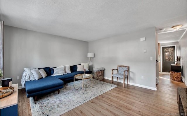 living room with a textured ceiling, wood finished floors, and baseboards