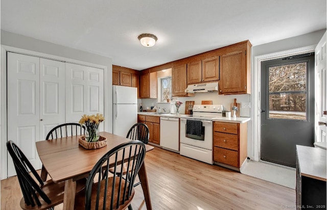 kitchen featuring brown cabinetry, light wood-type flooring, white appliances, and under cabinet range hood