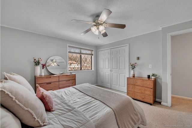 bedroom featuring a closet, light colored carpet, ceiling fan, a textured ceiling, and baseboards