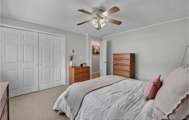 bedroom with a ceiling fan, ornamental molding, carpet, a textured ceiling, and a closet