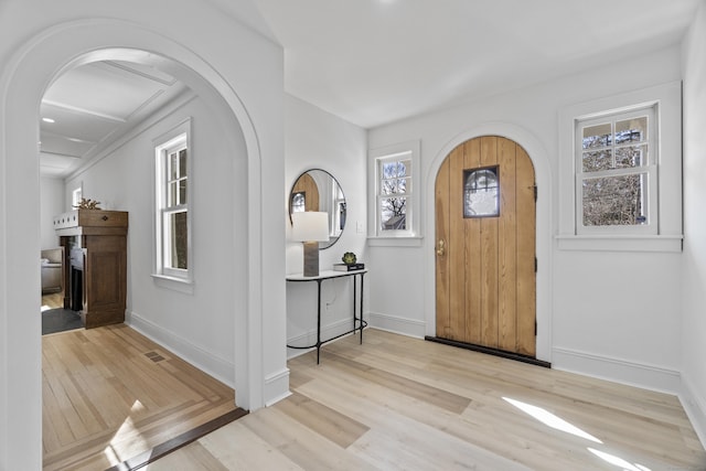 foyer entrance with arched walkways and wood finished floors