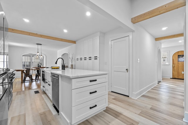 kitchen featuring arched walkways, stainless steel dishwasher, light wood-style floors, white cabinets, and beamed ceiling