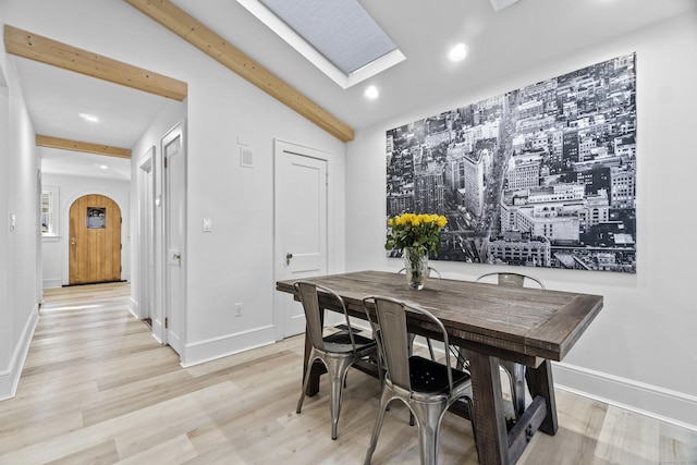 dining room with light wood-type flooring, baseboards, visible vents, and arched walkways