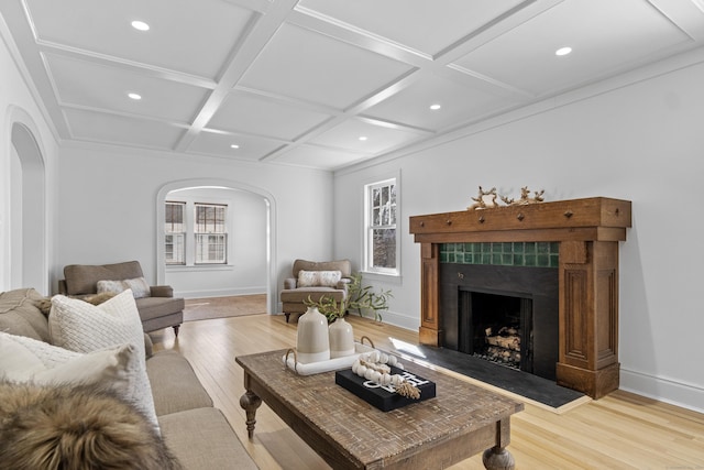 living room with a wealth of natural light, arched walkways, coffered ceiling, and a fireplace