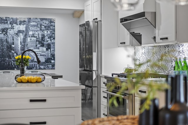 kitchen with stainless steel appliances, light countertops, backsplash, and white cabinetry