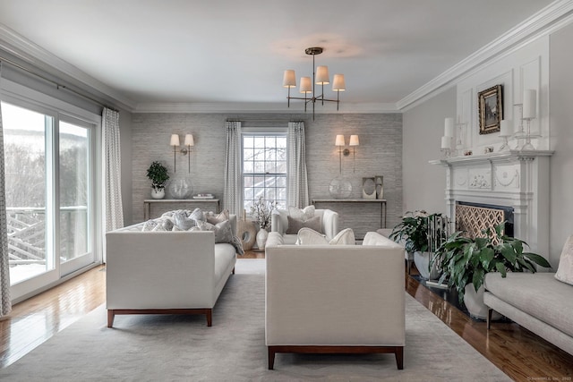 living room with a notable chandelier, a fireplace, wood finished floors, and crown molding