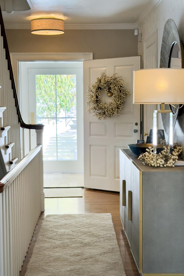 interior space featuring stairs, wood finished floors, and crown molding