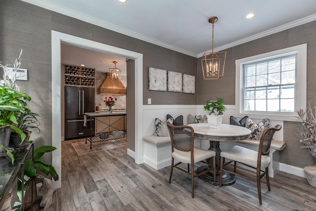 dining room featuring a wainscoted wall, breakfast area, wood finished floors, and ornamental molding