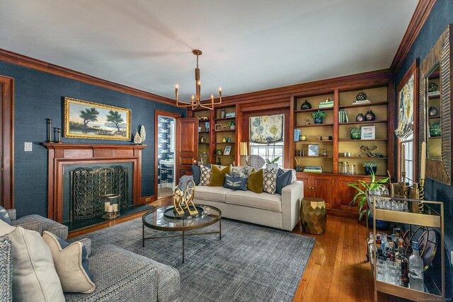 living area featuring hardwood / wood-style flooring, a fireplace, ornamental molding, and a notable chandelier