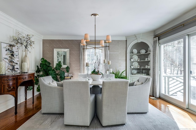 dining room featuring a notable chandelier, a wealth of natural light, crown molding, and wood finished floors