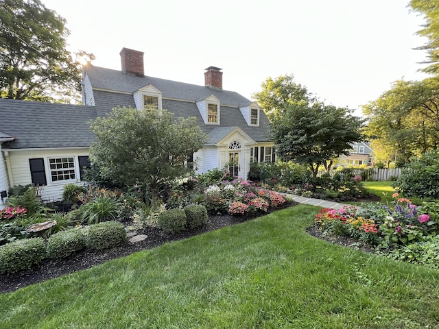 view of front of property with roof with shingles, a front yard, a chimney, and a gambrel roof