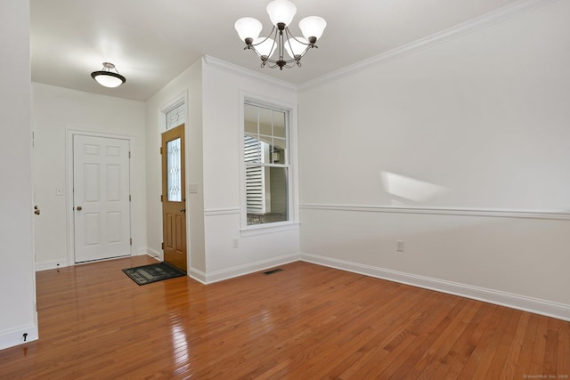 entrance foyer featuring ornamental molding, a notable chandelier, and wood-type flooring