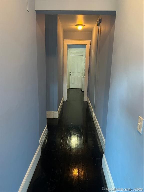 hallway featuring dark wood-style floors and baseboards