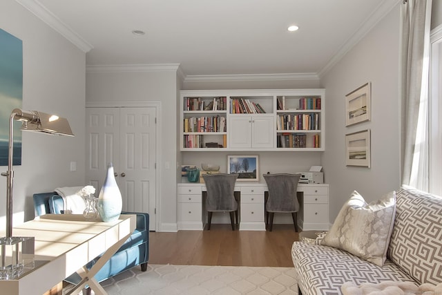 office area featuring ornamental molding, built in desk, and wood-type flooring