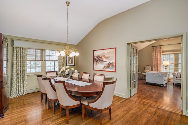 dining space featuring hardwood / wood-style floors, vaulted ceiling, a baseboard heating unit, and a notable chandelier