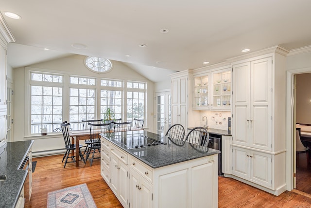 kitchen featuring white cabinetry, black electric cooktop, a kitchen island, and vaulted ceiling