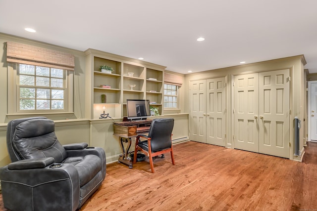 office featuring baseboard heating, light hardwood / wood-style floors, a wealth of natural light, and crown molding