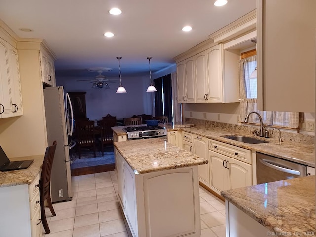 kitchen with light stone counters, stainless steel appliances, a sink, and decorative light fixtures