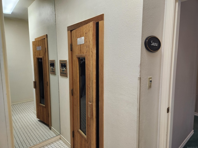 corridor with light tile patterned floors and baseboards