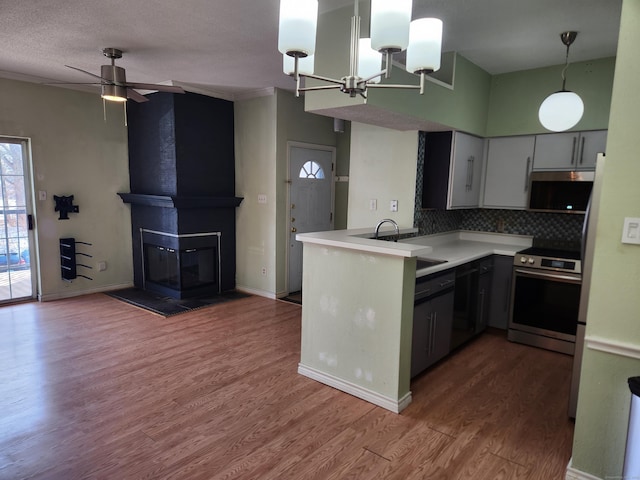 kitchen featuring a peninsula, light countertops, hanging light fixtures, stainless steel electric range, and gray cabinets