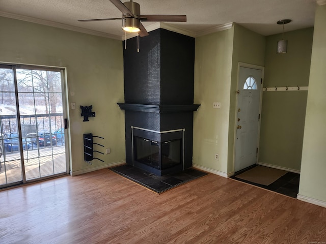 unfurnished living room with ornamental molding, a fireplace, wood finished floors, and baseboards