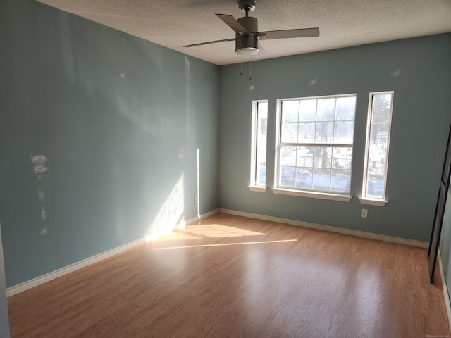 unfurnished room featuring a textured ceiling, ceiling fan, light wood-style flooring, and baseboards