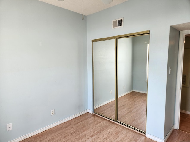 unfurnished bedroom with a closet, visible vents, baseboards, and light wood finished floors