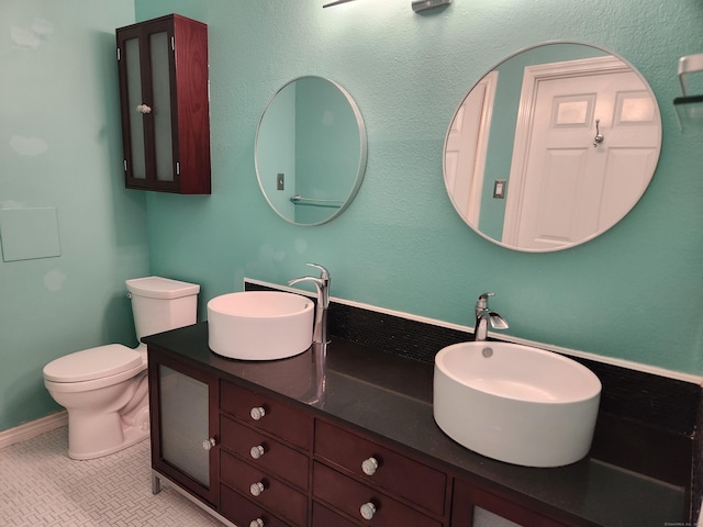 bathroom featuring toilet, tile patterned flooring, double vanity, and a sink