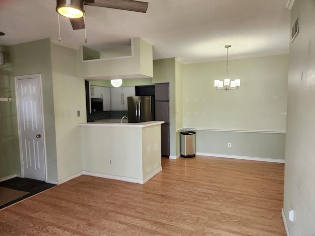 kitchen featuring visible vents, light wood-style flooring, freestanding refrigerator, a peninsula, and light countertops